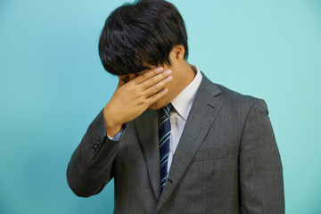 目元を抑えるスーツを着た日本人ビジネスマン