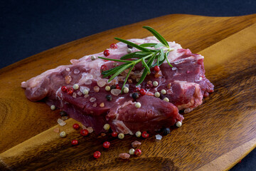 Raw steak and ingredients on a dark wooden cutting board