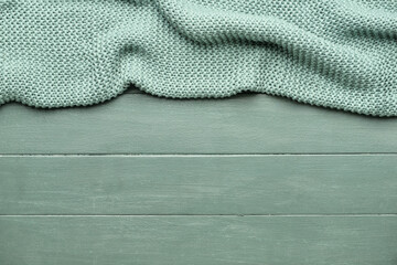 Knitted plaid on color wooden background