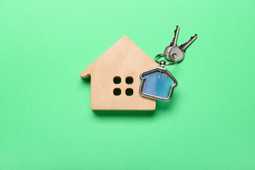Figure of house and keys with keychain on color background