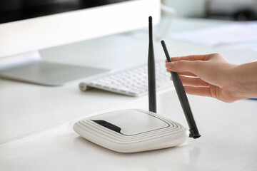 Female hand and wi-fi router on table in office