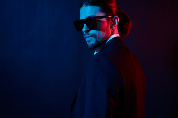 handsome man in a jacket posing self confidence sunglasses dark background