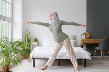 Pregnant Muslim woman doing yoga at home