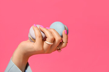 Woman with beautiful manicure and stylish jewelry holding macarons on color background