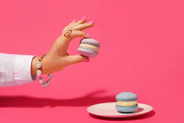 Poster Elegant woman with beautiful manicure and stylish jewelry holding macaron on color background © Pixel-Shot