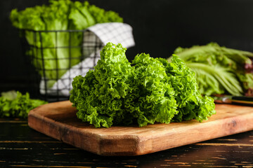 Board with fresh lettuce on dark wooden table