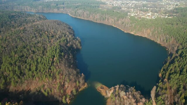 AERIAL: Lake Surounded with Green Pine Forets During Chilly Sunny Autumn Day