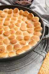 Frying pan with tasty S'mores dip on light background, closeup