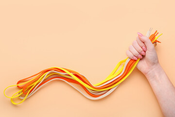 Woman holding many different shoe laces on color background, closeup