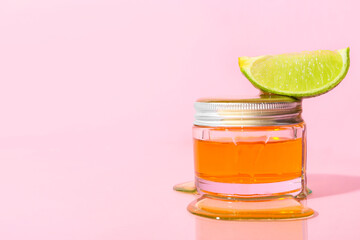 Jar of cosmetic product, slice of lime and honey on color background
