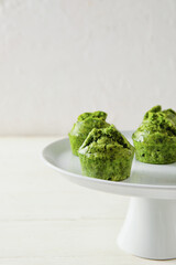 Stand with tasty spinach muffins on light background