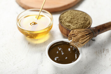 Bowl with hojicha powder, honey and chasen on light background