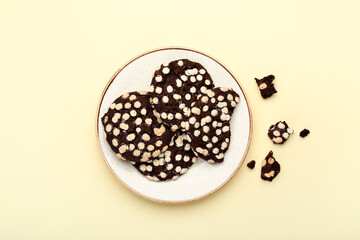 Plate with delicious chocolate cookies on color background