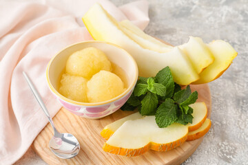 Bowl with sorbet, melon pieces and mint on light background