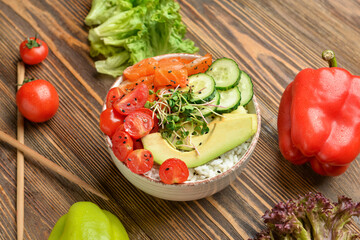 Tasty poke bowl and ingredients on wooden background