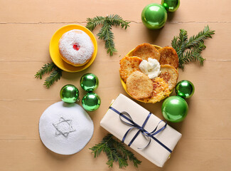 Symbols of Hanukkah with gift and Christmas decor on color wooden background