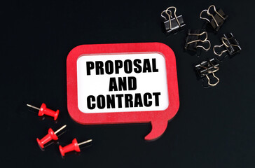On a black surface, office supplies and a red plaque with the inscription - Proposal and contract