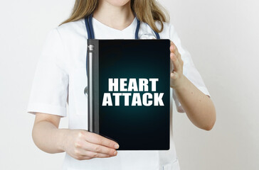 Fototapeta na wymiar The doctor is holding a tablet with the inscription -HEART ATTACK