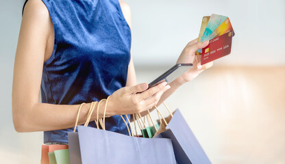 Young beautiful happy woman holding colorful shopping bags and showing her credit cards