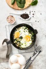 Frying pan with tasty Shakshouka and ingredients on light background
