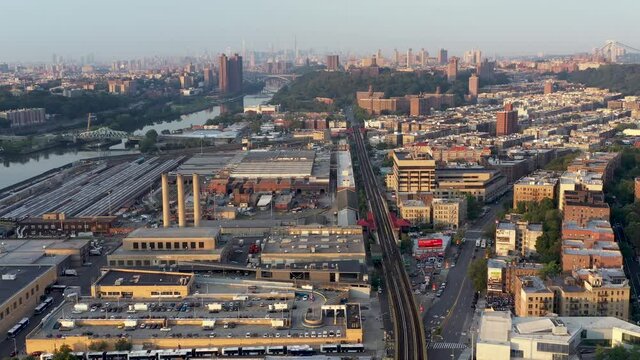 Aerial trucking shot over industrial part of upper Manhattan New York City at golden hour.  Midtown skyline in the far distance.