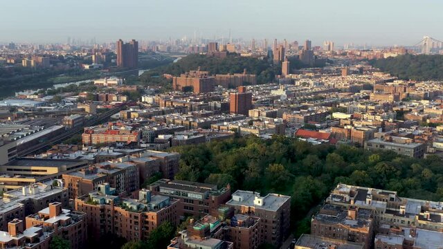 Wide angle aerial flight over the Inwood neighborhood of upper Manhattan New York City towards Washington Heights at golden hour