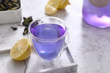 Glass cup of blue tea on light background