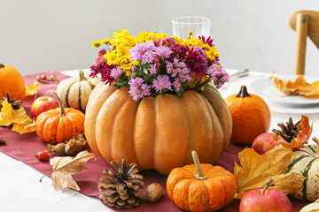 Beautiful bouquet of autumn flowers in pumpkin on table