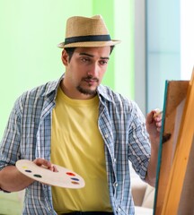 Young male artist working on new painting in his studio
