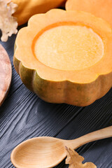 Tasty soup served in pumpkin on black wooden background