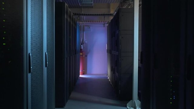 Motion shot of dark database corridor and equipment racks working on modern render farm spbas. Close-up view of hardware shelves with flashing processors running and supporting networks and systems in