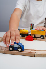 The boy is playing on the toy wooden road. Top view. Child boy playing in his room with a toy train. Kid's hands close up