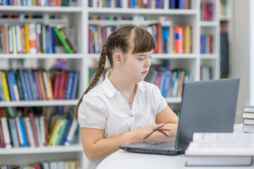 Girl with special needs uses a laptop at school