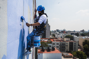 Men working on a building using rappelling equipment - obrazy, fototapety, plakaty
