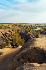 Two people are sitting in tourist chairs at a table in the mountains. Lunch on the way. Autumn landscape. Travel the mountains. Place for text insertion