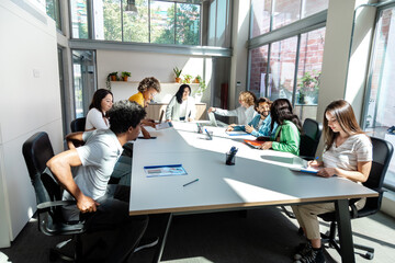 The business meeting starts in the office. Multiracial young adult coworkers interact in conference...