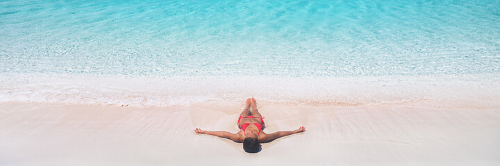 Beach vacation dream Caribbean travel destination bikini woman sunbathing relaxing lying down on...