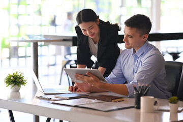 Smiling businessman holding digital tablet and shearing information to colleague.