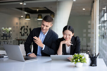 Two smiling business colleagues sitting in modern workplace and working together.