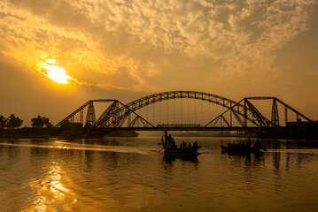Fototapeta na wymiar sunset in the river with steel bridge, The Lansdowne Bridge is a 19th-century bridge that spans the Indus River between the cities of Sukkur and Rohri, in the Sindh province of Pakistan.