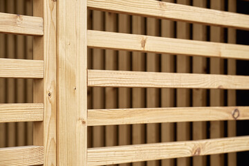 Stylish decorative partition made of thin wooden planks stands on contemporary country house terrace on spring day closeup