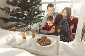 Obraz na płótnie Canvas Beautiful family sitting on bed hugging and eating cookies