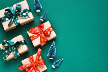 Flat lay composition Christmas gifts with decorative trees on green background. Copy space. New year, Christmas concept. Template, mockup. Greeting card. Top view.