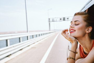 cheerful woman peeking out of the car window trip road travel