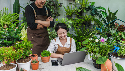 Young gardener couple use smartphone and laptop online with houseplant
