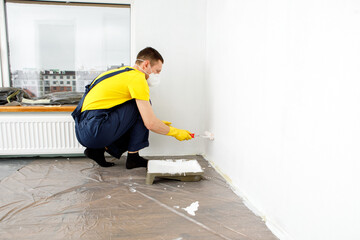 the man paints the walls and the ceiling in white color Painting and repair of the room.