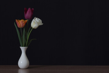 Three tulips in a vase on the table.