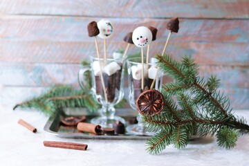Christmas sweets, black chocolate and meringue on sticks in glass cups, spices, spruce branches on a wooden background, the concept of a holiday, winter, New Year 
