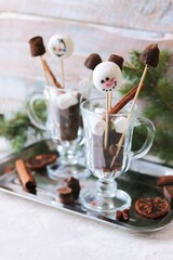 Christmas sweets, black chocolate and meringue on sticks in glass cups, spices, spruce branches on a wooden background, the concept of a holiday, winter, New Year 