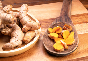 Turmeric root in wooden plate, Turmeric Thai herb on a wooden table background.